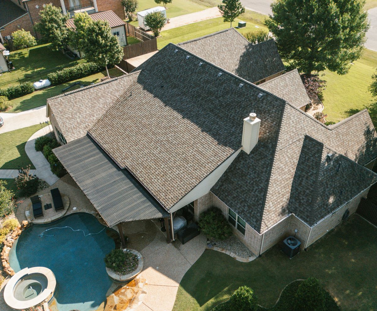 Aerial view of a new shingle roof on a house with a pool