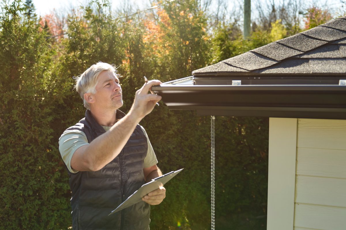 A man standing on steps inspecting house roof